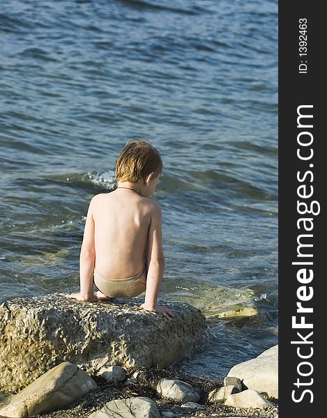 The child plays on a stone beach. The child plays on a stone beach