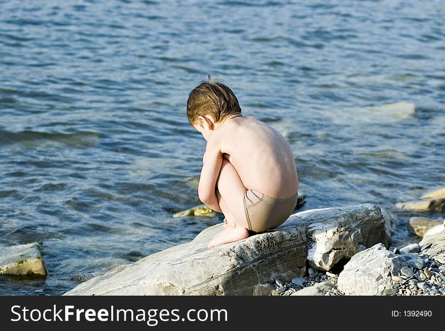 The child plays on a stone beach. The child plays on a stone beach