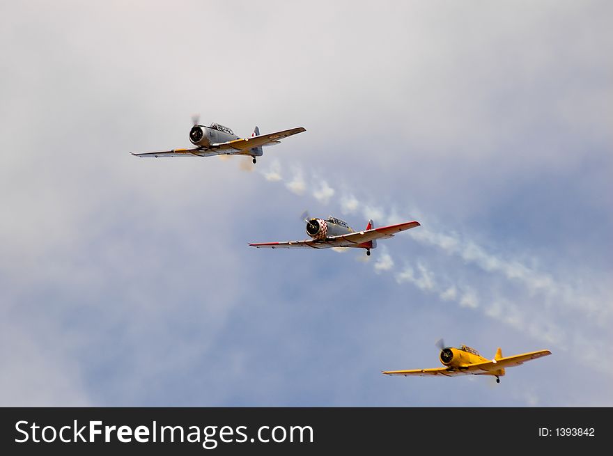 Three Harvard T-6's fly past in formation during an air show. Three Harvard T-6's fly past in formation during an air show.