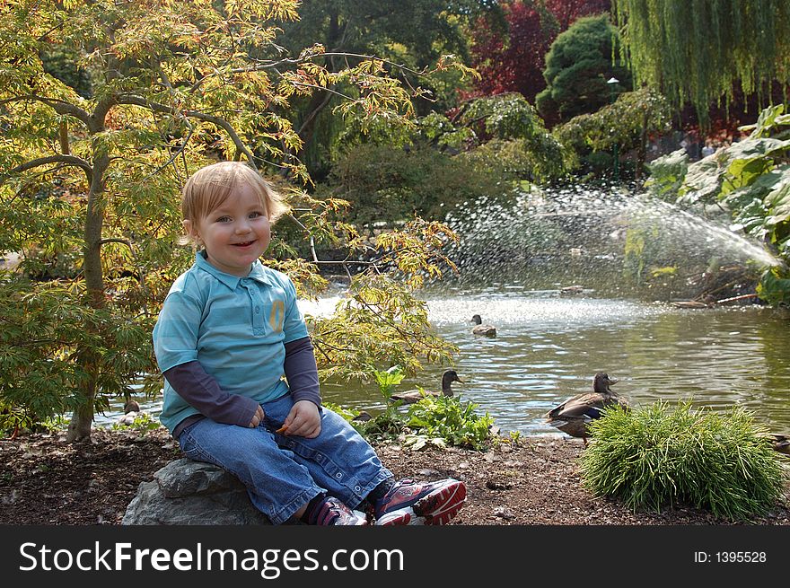 An outdoor portrait of a smiling boy with a pond and ducks. An outdoor portrait of a smiling boy with a pond and ducks