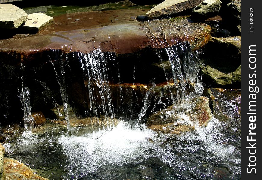 Flowing water over a mini waterfall at the park. Flowing water over a mini waterfall at the park