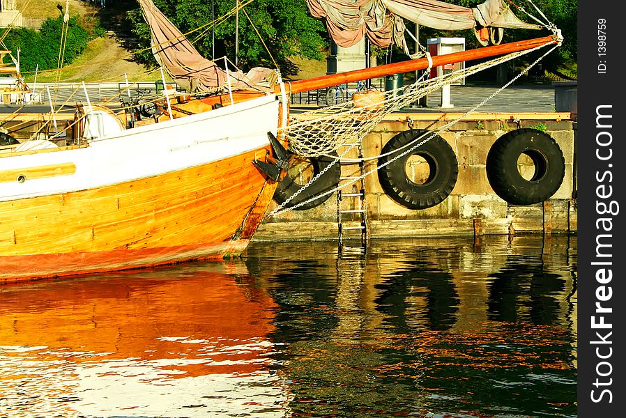 A vintage sailing ship  moored in a harbor. Warm lighting. Beautiful reflexes.