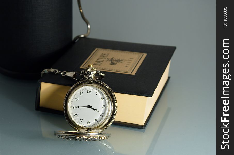 Pocket watch and book on glass table. Pocket watch and book on glass table