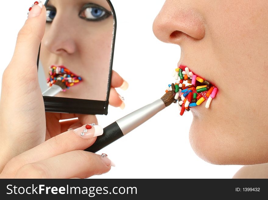 Woman brushing on lipstick made of candy. Woman brushing on lipstick made of candy.
