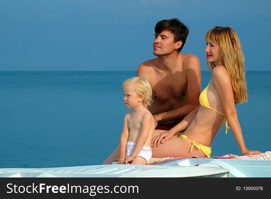 Young parents with the child sit on a beach