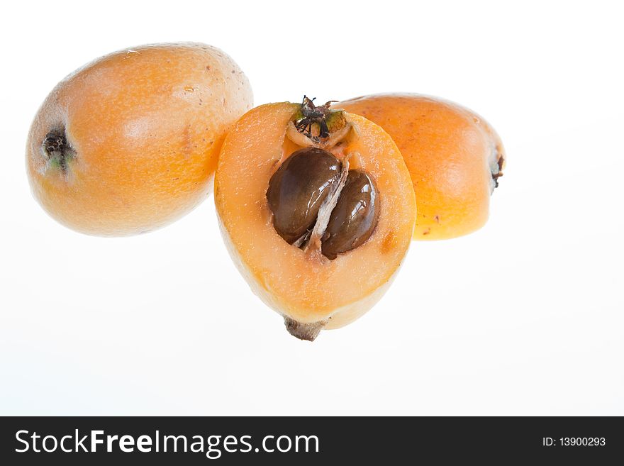 Two loquats, one halved, against a white background. Two loquats, one halved, against a white background