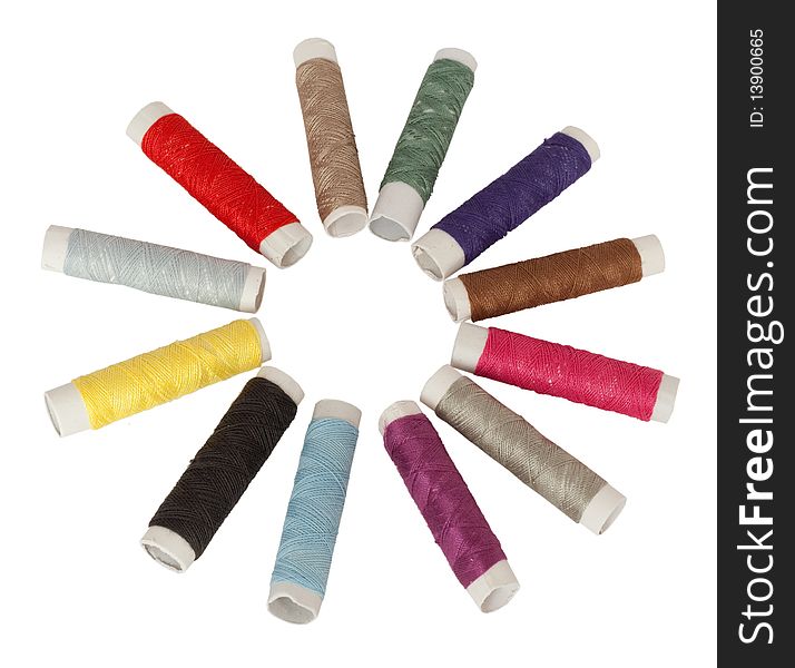 Several colored spools of threads laid out in a circle. Isolated in white.