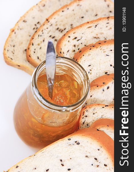 Spread slice brown wholewheat bread and orange jam on white background