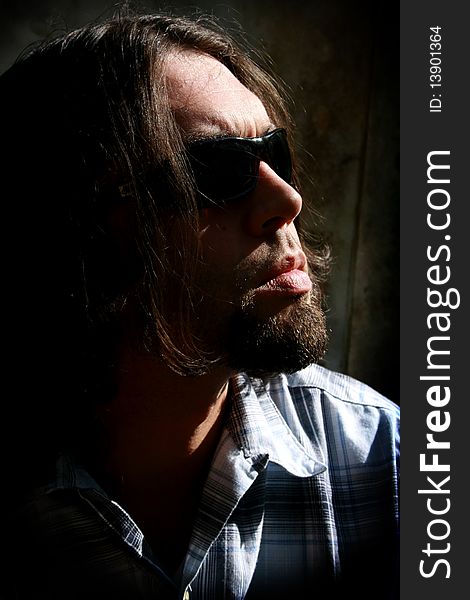 Long haired man with sunglasses in a low key shot. Long haired man with sunglasses in a low key shot