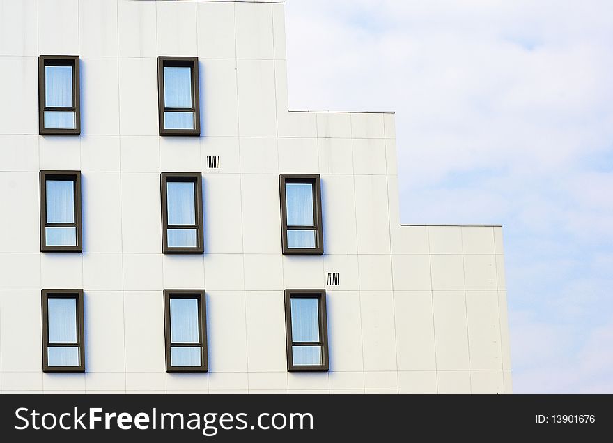 Office building detail with windows against blue sky with clouds. Office building detail with windows against blue sky with clouds.