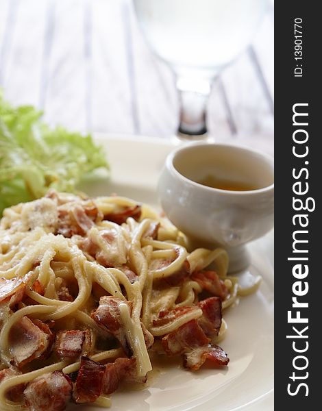 A plate of spaghetti carbonara taken at an outdoor restaurant, focus on spaghetti