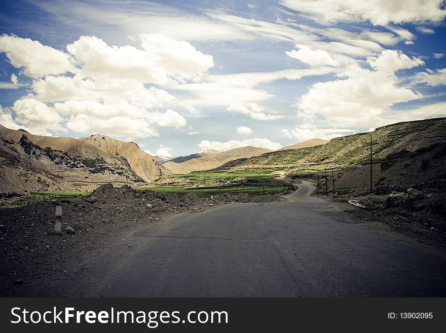 Road in Himalaya mountains. Blue sky with white cloads and mountain range on background.