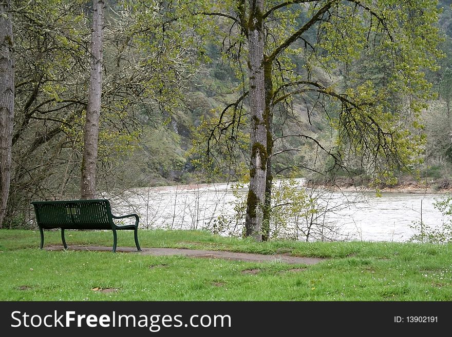 An empty park bench by a river.