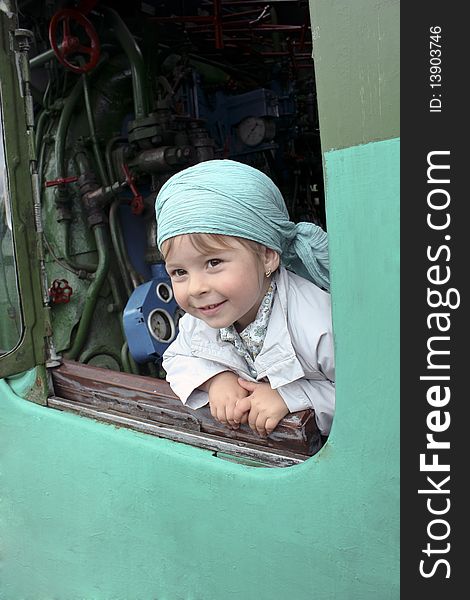 The girl looks out of the opened window of a steam locomotive. The girl looks out of the opened window of a steam locomotive