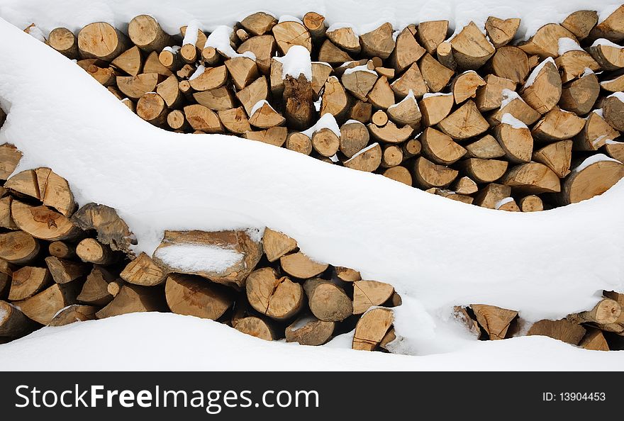 Firewood stashed in winter under a blanket of snow