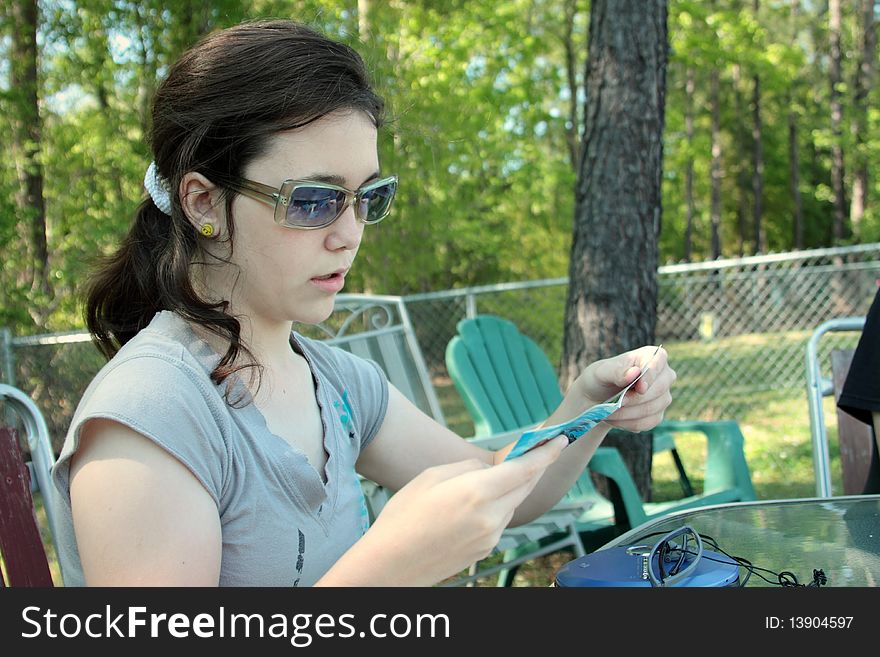 Teen girl reading cd insert with sun glasses on
