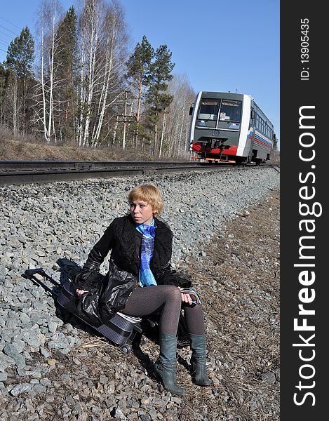 Woman sitting on a railway embankment, coming from behind a small locomotive. Woman sitting on a railway embankment, coming from behind a small locomotive