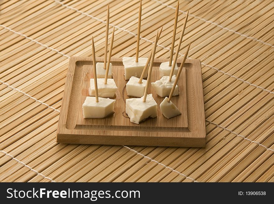 Seved white cheese on a wooden board with toothpics