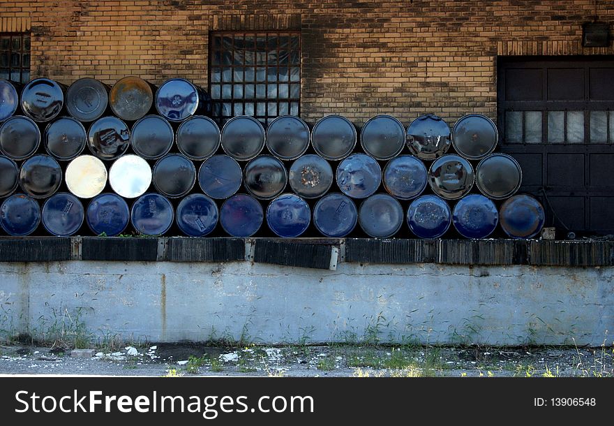 Stacks of blue metal drums against an old brick building. Stacks of blue metal drums against an old brick building