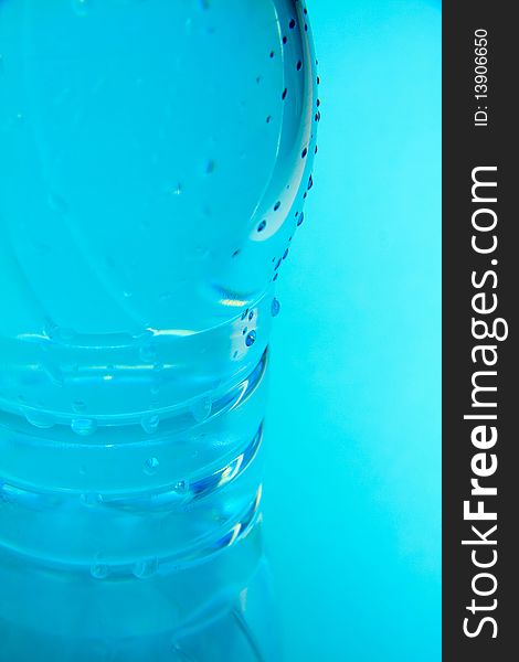 A plastic bottle filled with still water. Image isolated on light blue studio background. A plastic bottle filled with still water. Image isolated on light blue studio background.