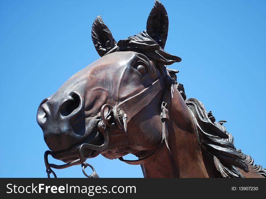 A bronze horse statue contrasted against the bright blue sky.