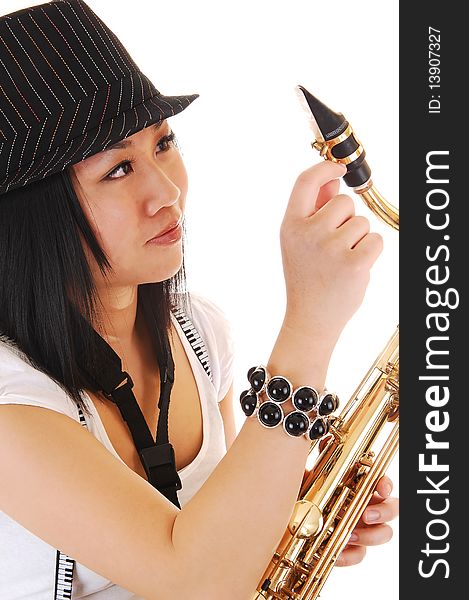 A young Asian woman with a hat on her black hair, fixing her saxophone in a closeup picture, for white background. A young Asian woman with a hat on her black hair, fixing her saxophone in a closeup picture, for white background.