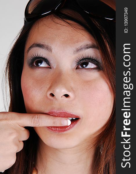 Closeup of the face of a lovely Asian woman with red lips and her finger in her mouth, with sunglasses on her forehead, for white background. Closeup of the face of a lovely Asian woman with red lips and her finger in her mouth, with sunglasses on her forehead, for white background.