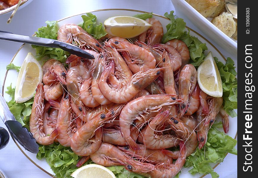 Fresh Prawns on salad leafs and lemon served in glass bowl