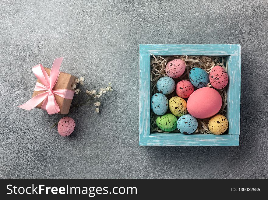 Colorful easter eggs in box and gift on table. Top view with copy space