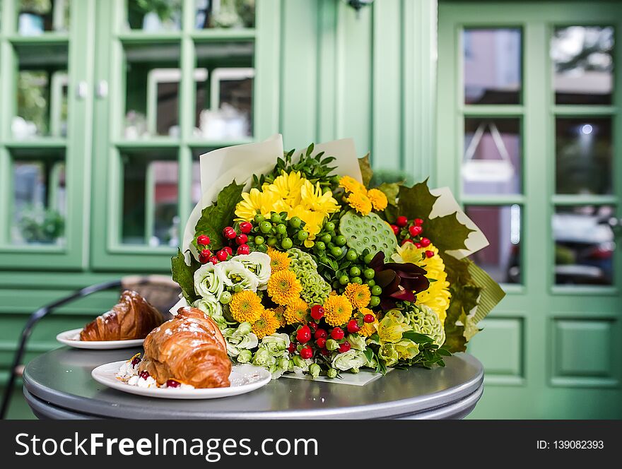 Bouquet of colorful flowers and dessert on table. Alstromeriya, lotus, hypericum, eustoma, celosia