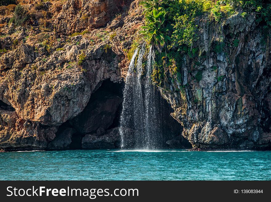 View of big waterfall at Mediterranean seacoast cliff and beach near Antalya, Turkey, summer