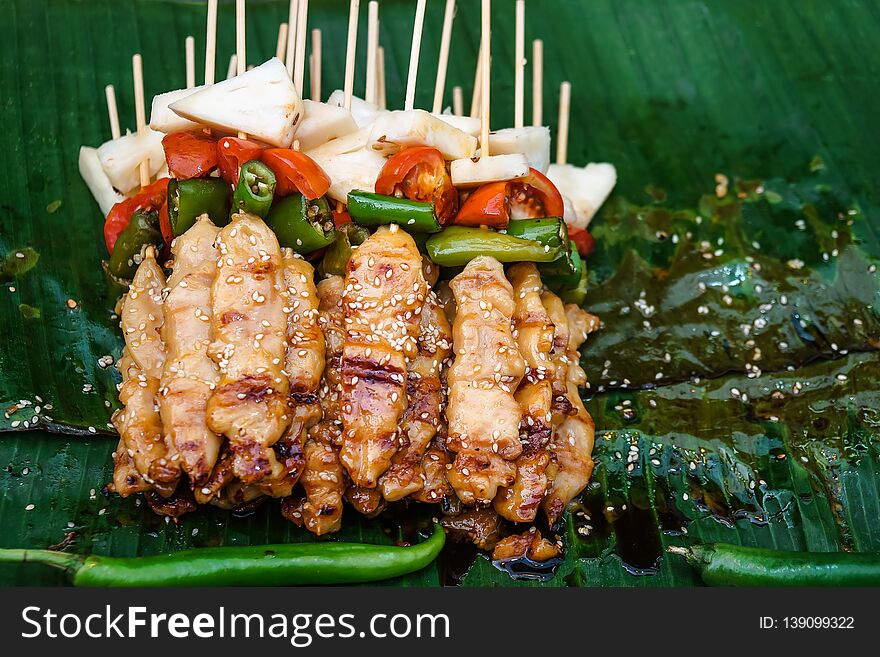 Close up Street food Grilled Chicken BBQ paste white sesame in wooden skewers with tomato pineapple pepper. Place on the tray with