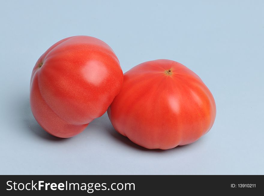 Two tomatoes in a light blue background