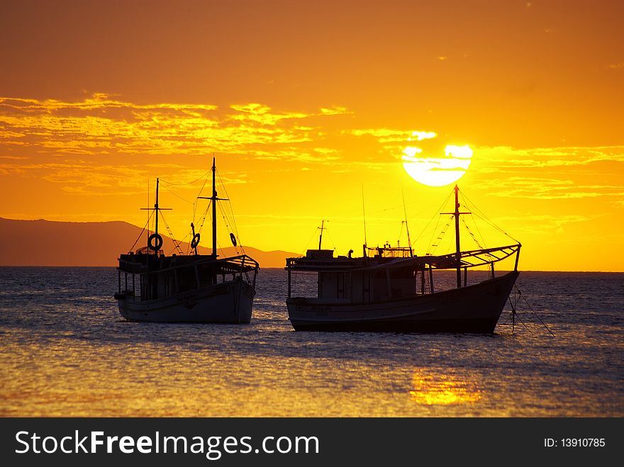 Two boats laying in a bay with a beautiful sunset in the background. Two boats laying in a bay with a beautiful sunset in the background.