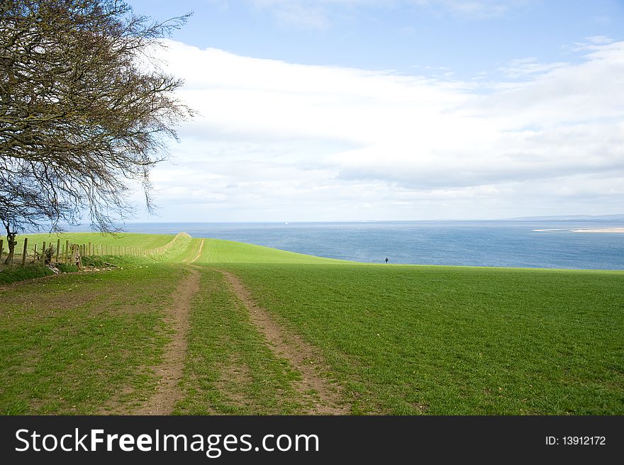 An image of a field of grass with a track beside the sea on the coast of North East Scotland. An image of a field of grass with a track beside the sea on the coast of North East Scotland.