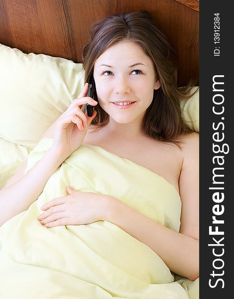 Young beautiful woman with mobile phone in the bed. Young beautiful woman with mobile phone in the bed