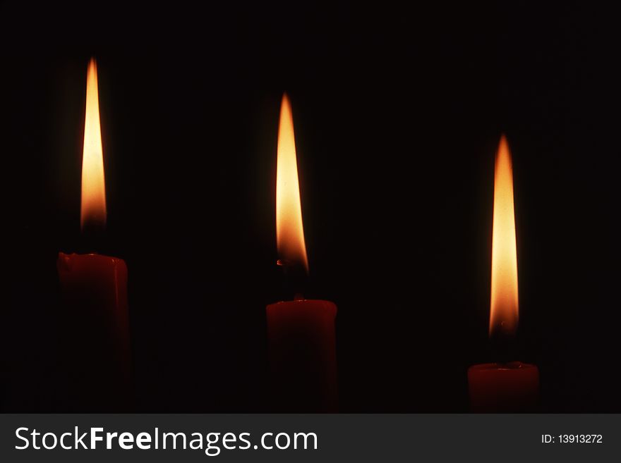 Three candles in dark background