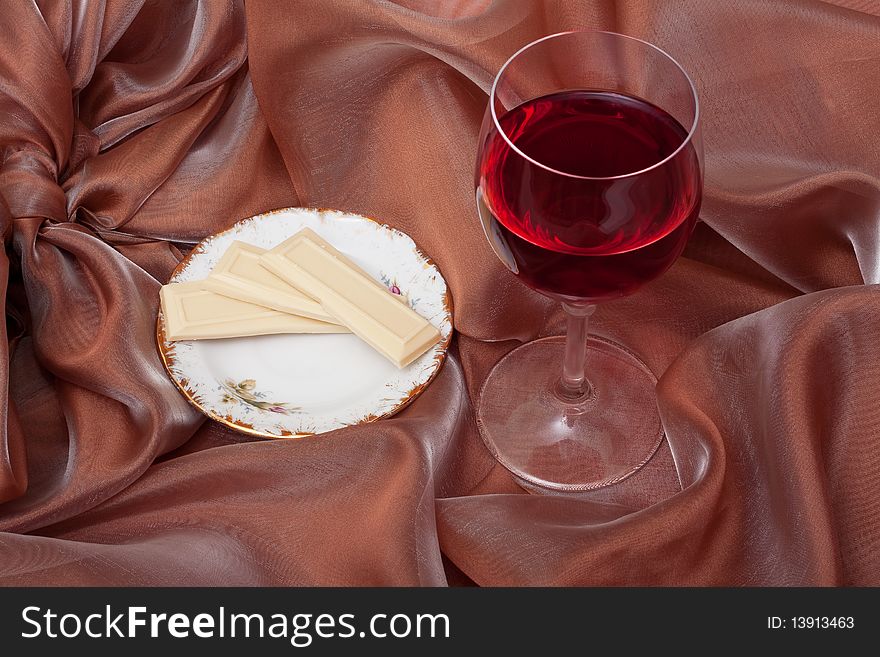 Pieces of white chocolate and wine on the background of beige organza. Pieces of white chocolate and wine on the background of beige organza