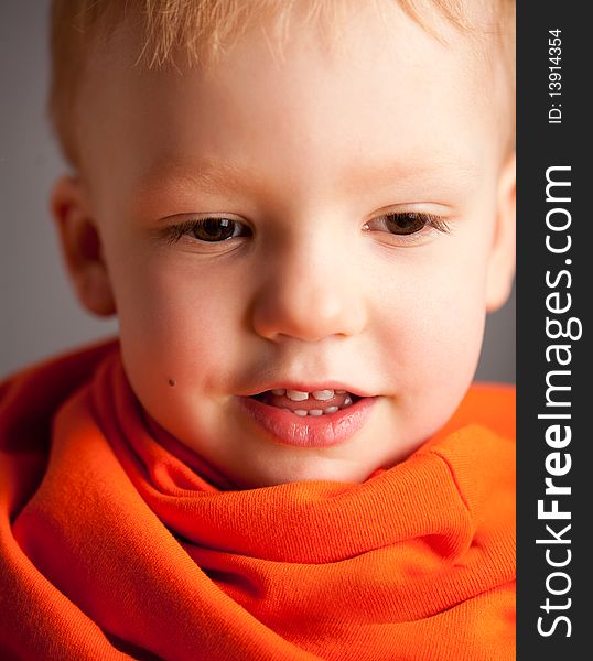 Portrait of emotional pretty little boy with orange scarf