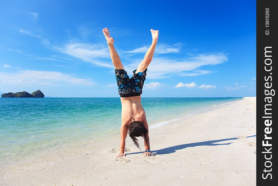 Casual guy doing the handstand on the beach