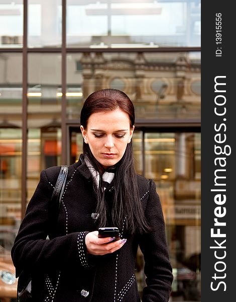 Business lady awaiting for somebody and writing sms on her mobile phone. Business lady awaiting for somebody and writing sms on her mobile phone