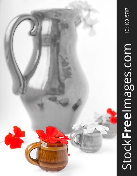 The big black-and-white jug and color mug with a red geranium. The big black-and-white jug and color mug with a red geranium