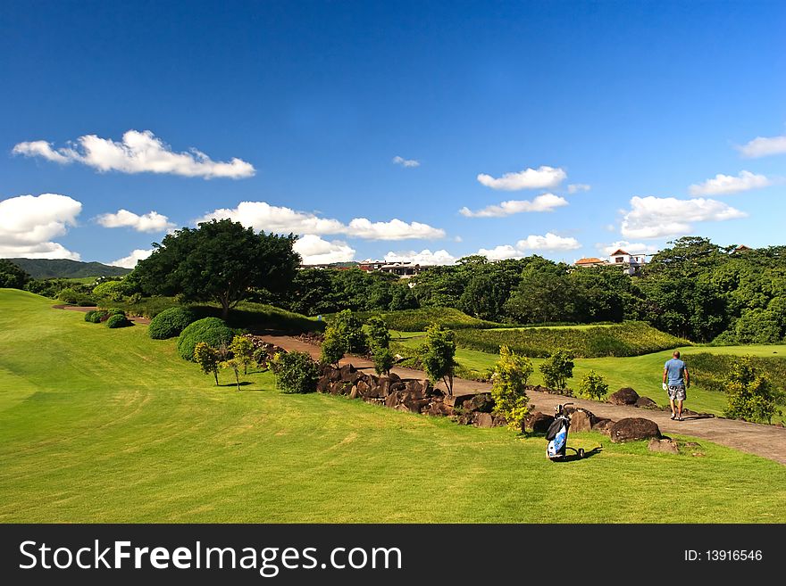 A golfer searching his ball in a beautiful greenery view of a golf field in Mauritius