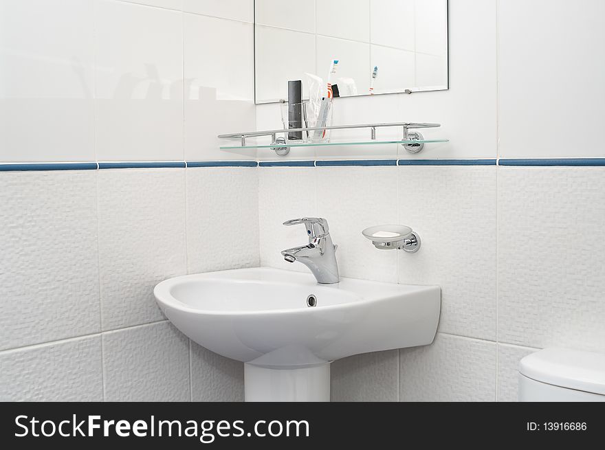 White bathroom with mirror and washbowl, faucet and tooth brushes. White bathroom with mirror and washbowl, faucet and tooth brushes