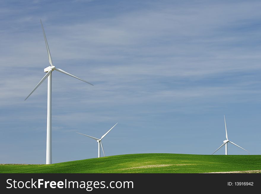 Windmills in a green meadow with cloudy sky. Windmills in a green meadow with cloudy sky