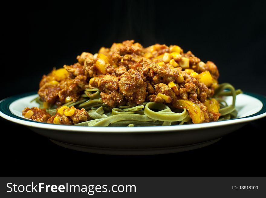 A plate of noodles and meat sauce on black background. A plate of noodles and meat sauce on black background.