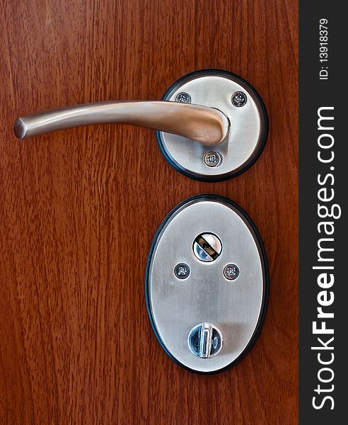 Silver door handle on brown wooden door