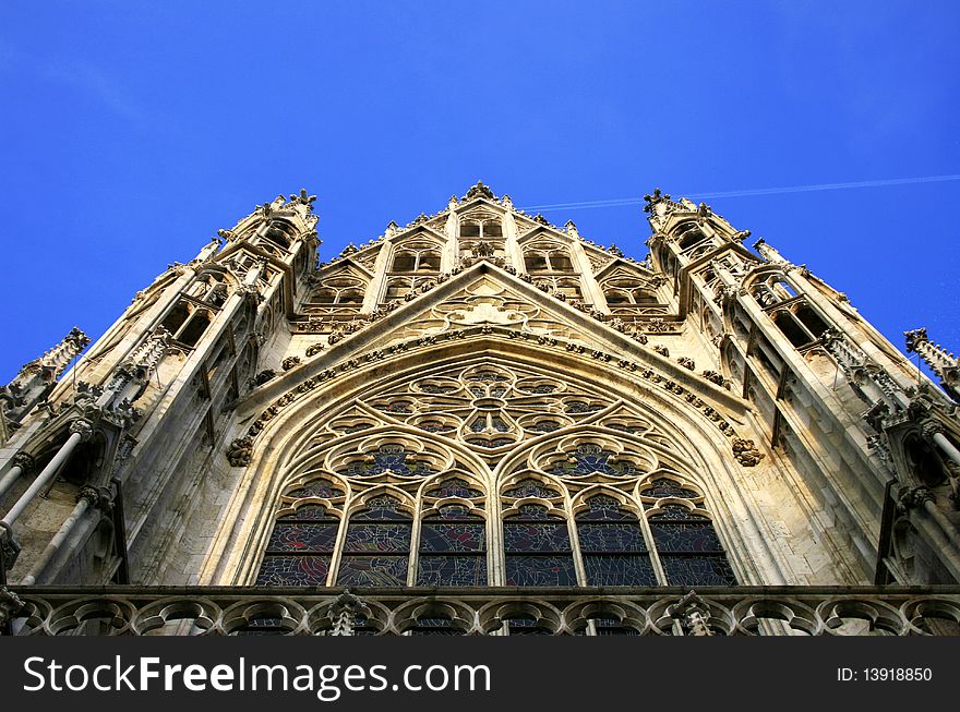 A typical Gothic Cathedral in the old medieval district of Vienna. The image shows a detail of a beautifully colored strained-glass window a trademark of the Gothic architecture. A typical Gothic Cathedral in the old medieval district of Vienna. The image shows a detail of a beautifully colored strained-glass window a trademark of the Gothic architecture.