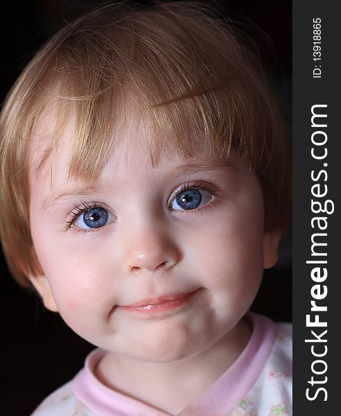 Portrait of a close-up little smiling child with big blue eyes.