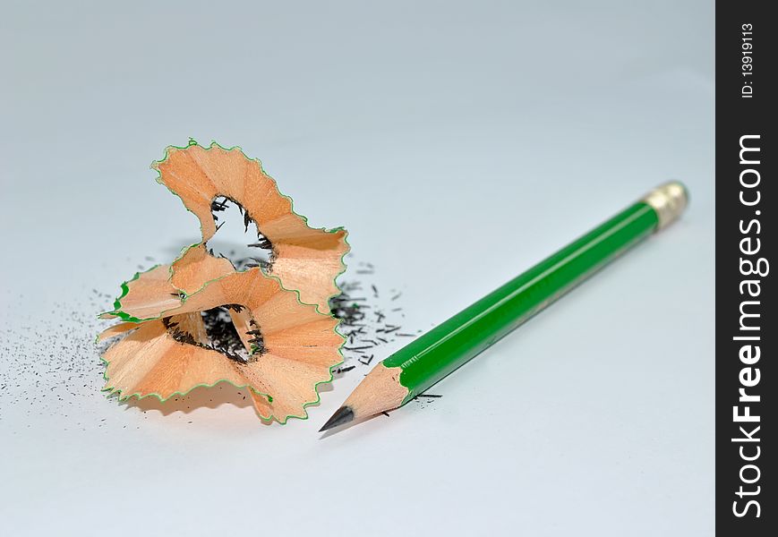 A sharpened green pencil with its shreds. A sharpened green pencil with its shreds.